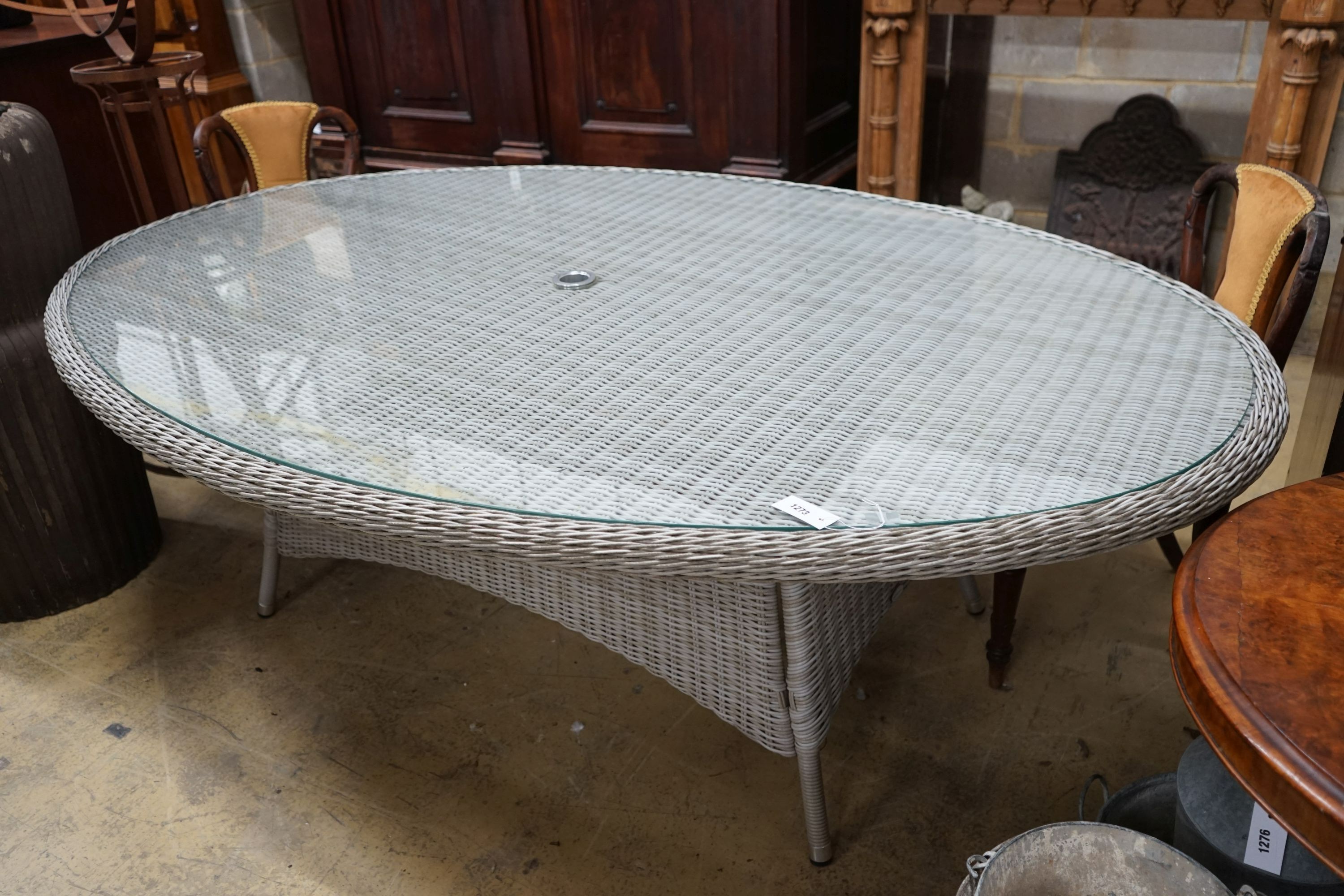 A Bramblecrest oval all weather rattan glass topped garden table, length 220cm, depth 144cm, height 73cm